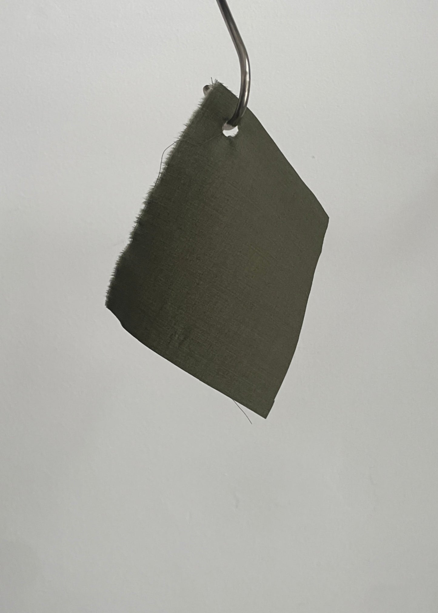 Dark green fabric sample hanging on a rod against a light gray background