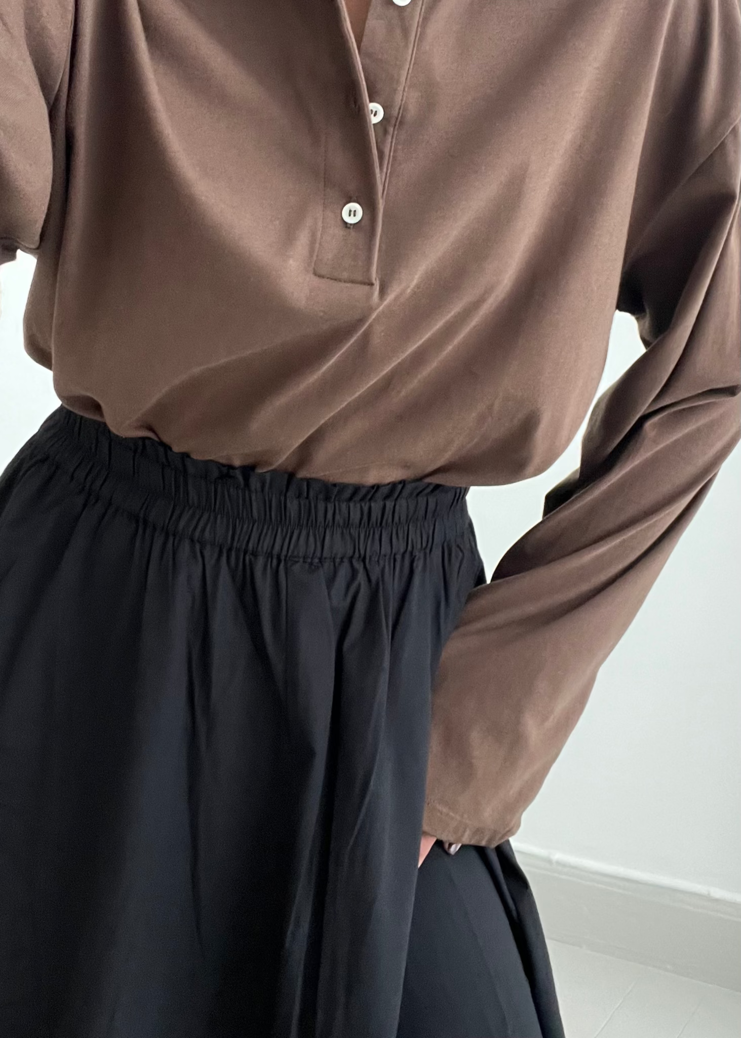 Person wearing a brown long-sleeve shirt with a collar against a white background