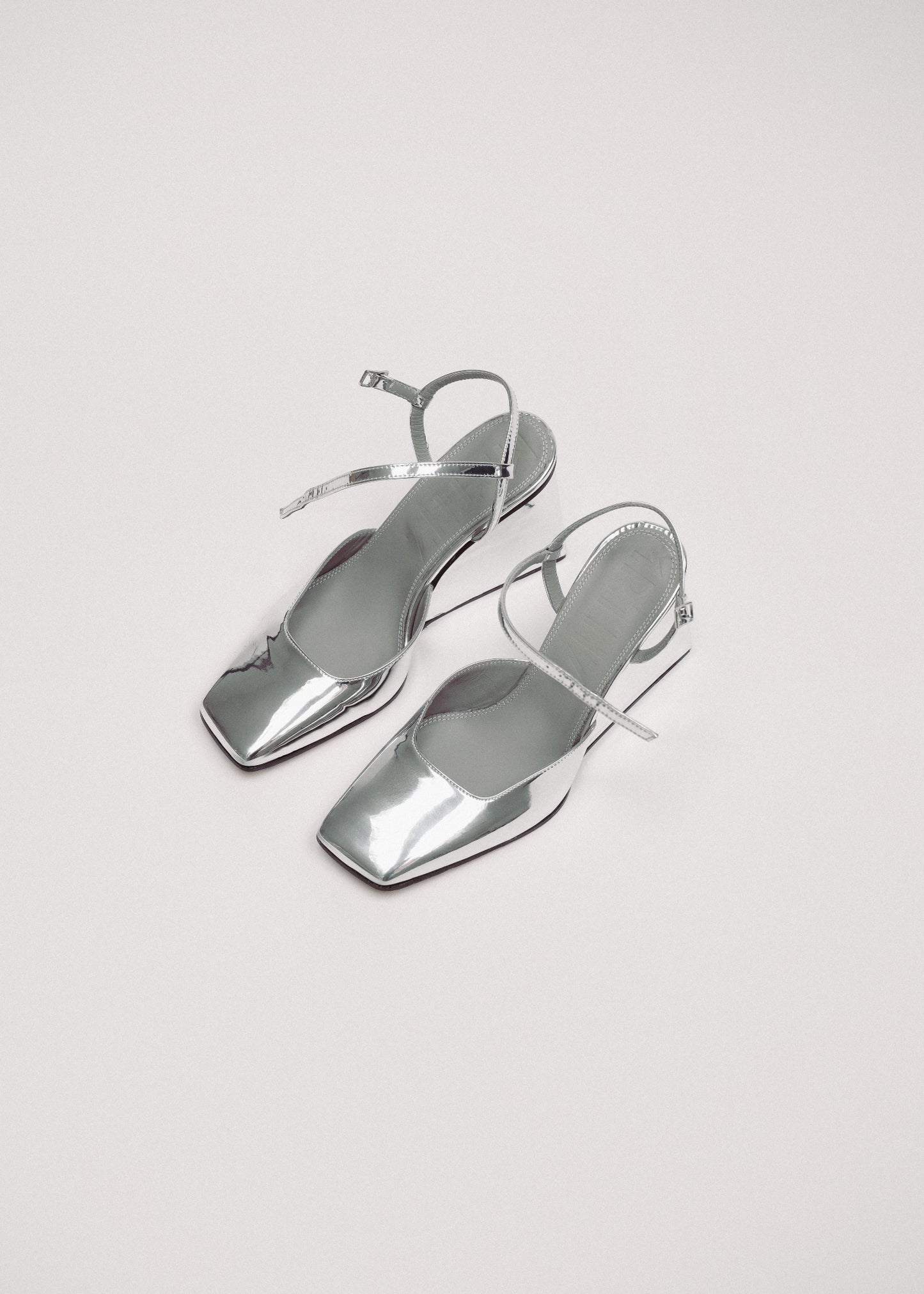 Pair of silver high-heeled shoes on a light gray background