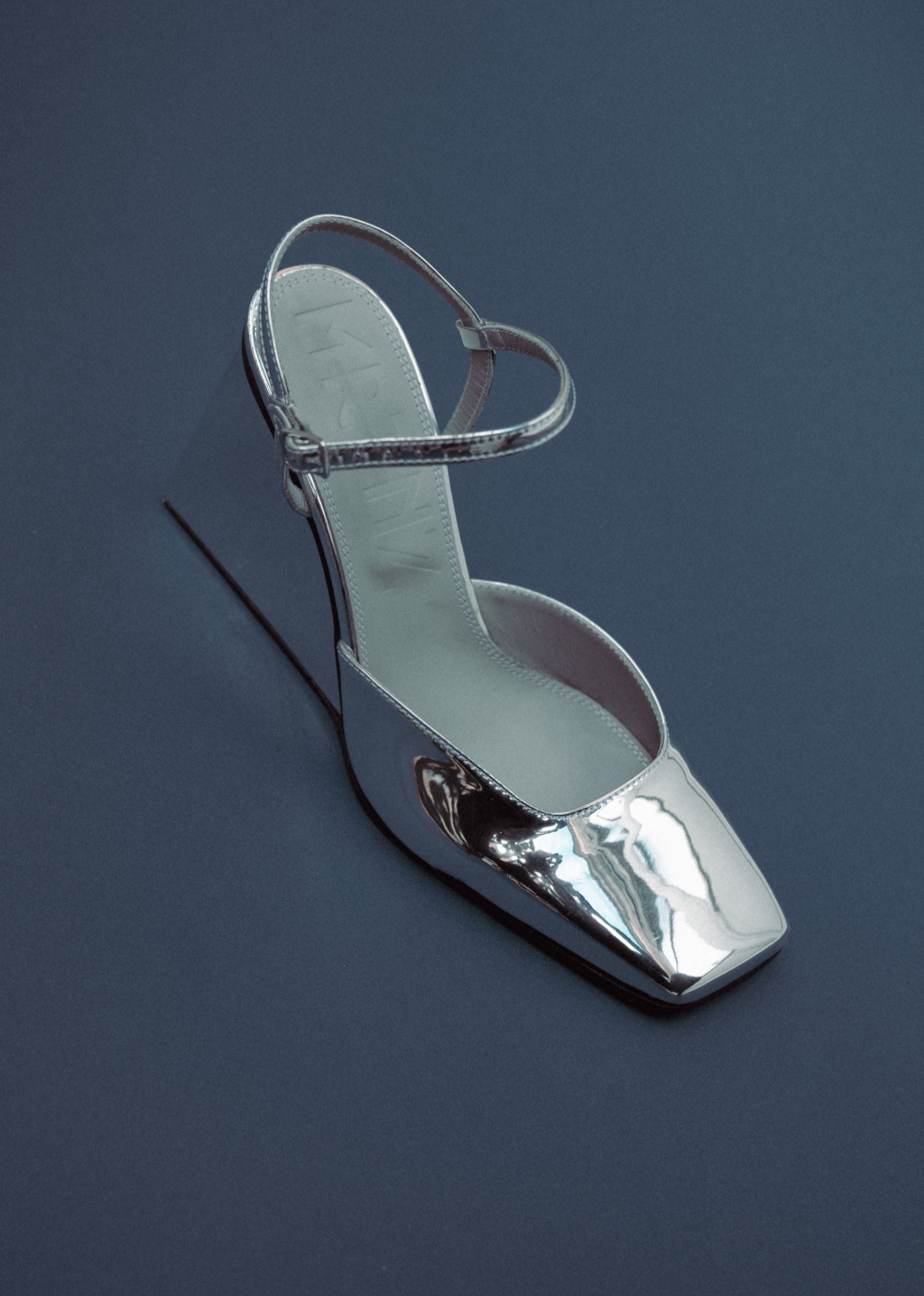 Silver high-heeled shoe on a dark blue background