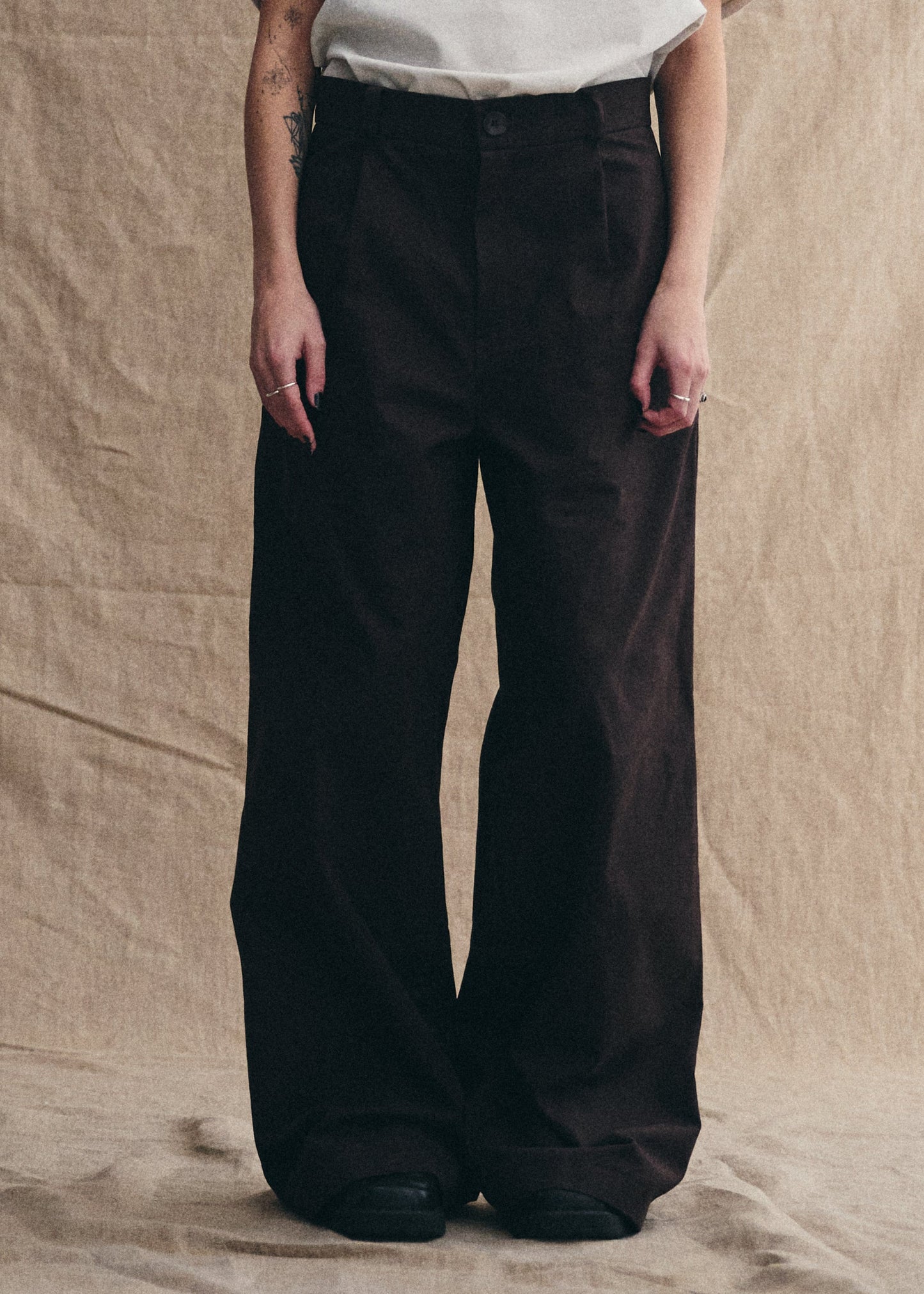 Person wearing black wide-leg pants against a beige background