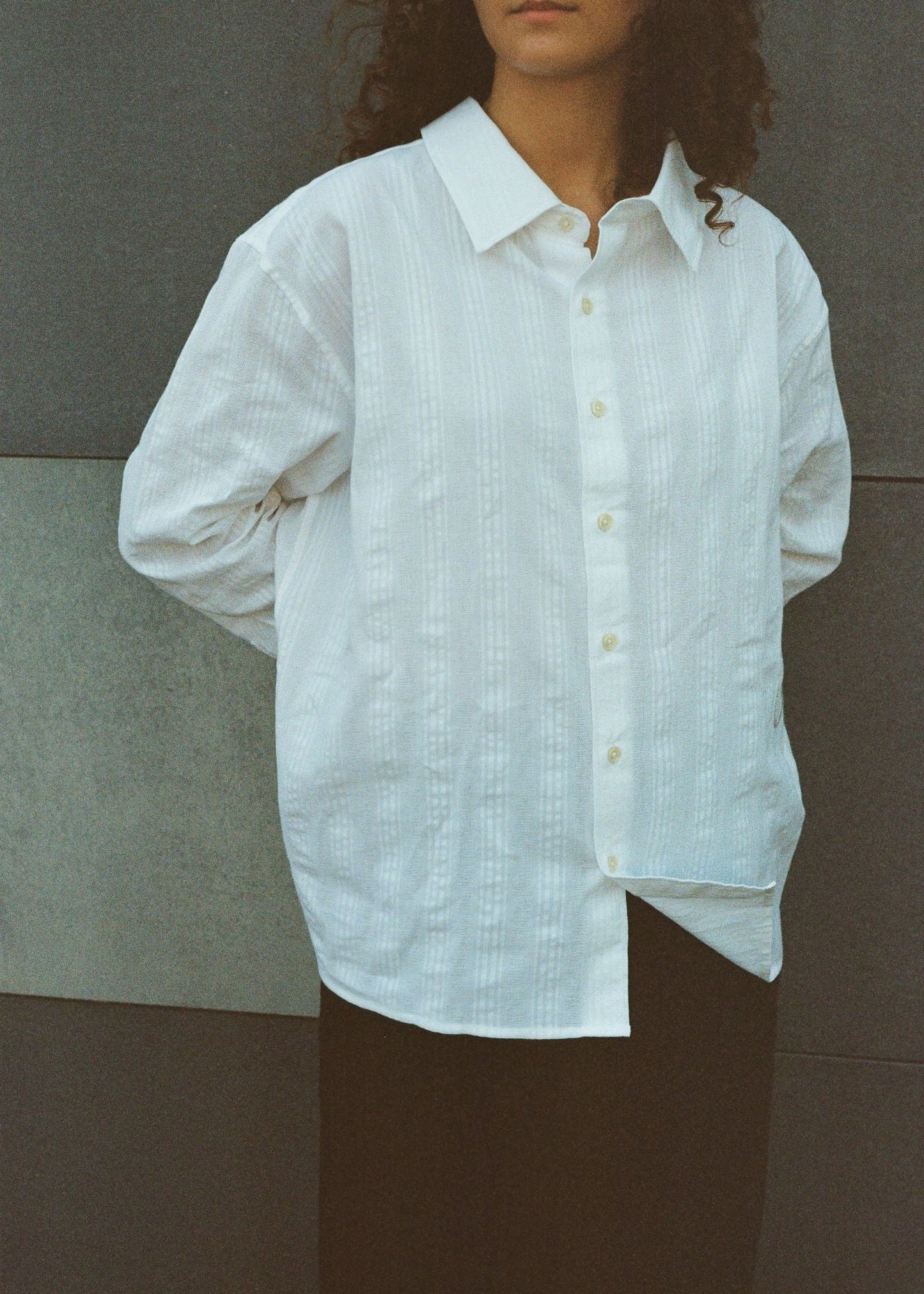 Person wearing a white button-up shirt against a neutral background