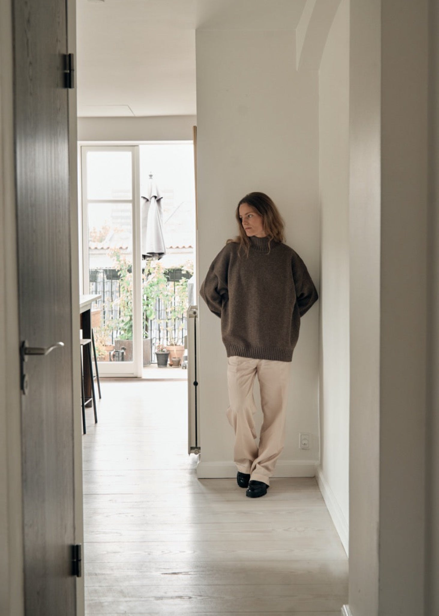 Person standing in a well-lit room with a view of the outdoors.