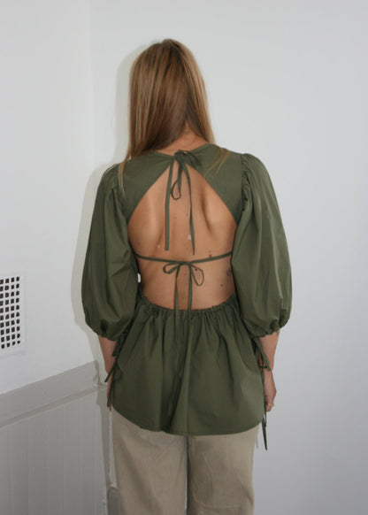 Person wearing a green occasion wear top on a white background