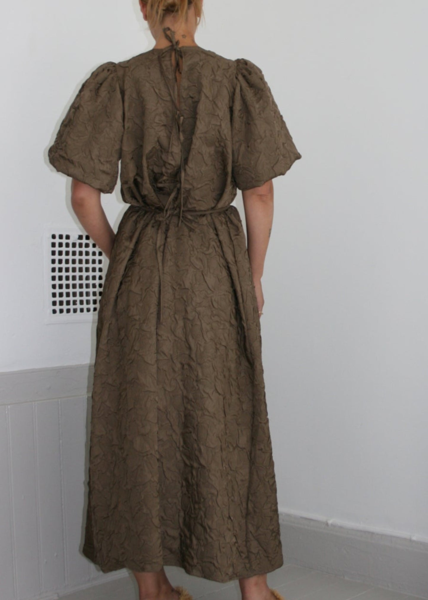 Person wearing a brown dress standing on a white floor