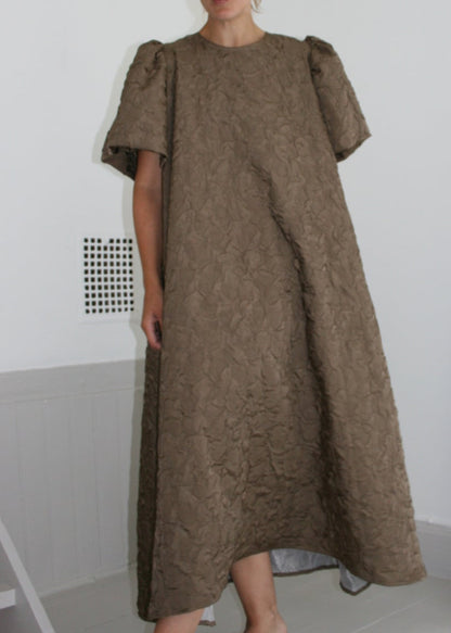Woman wearing a brown dress standing in front of a mirror.