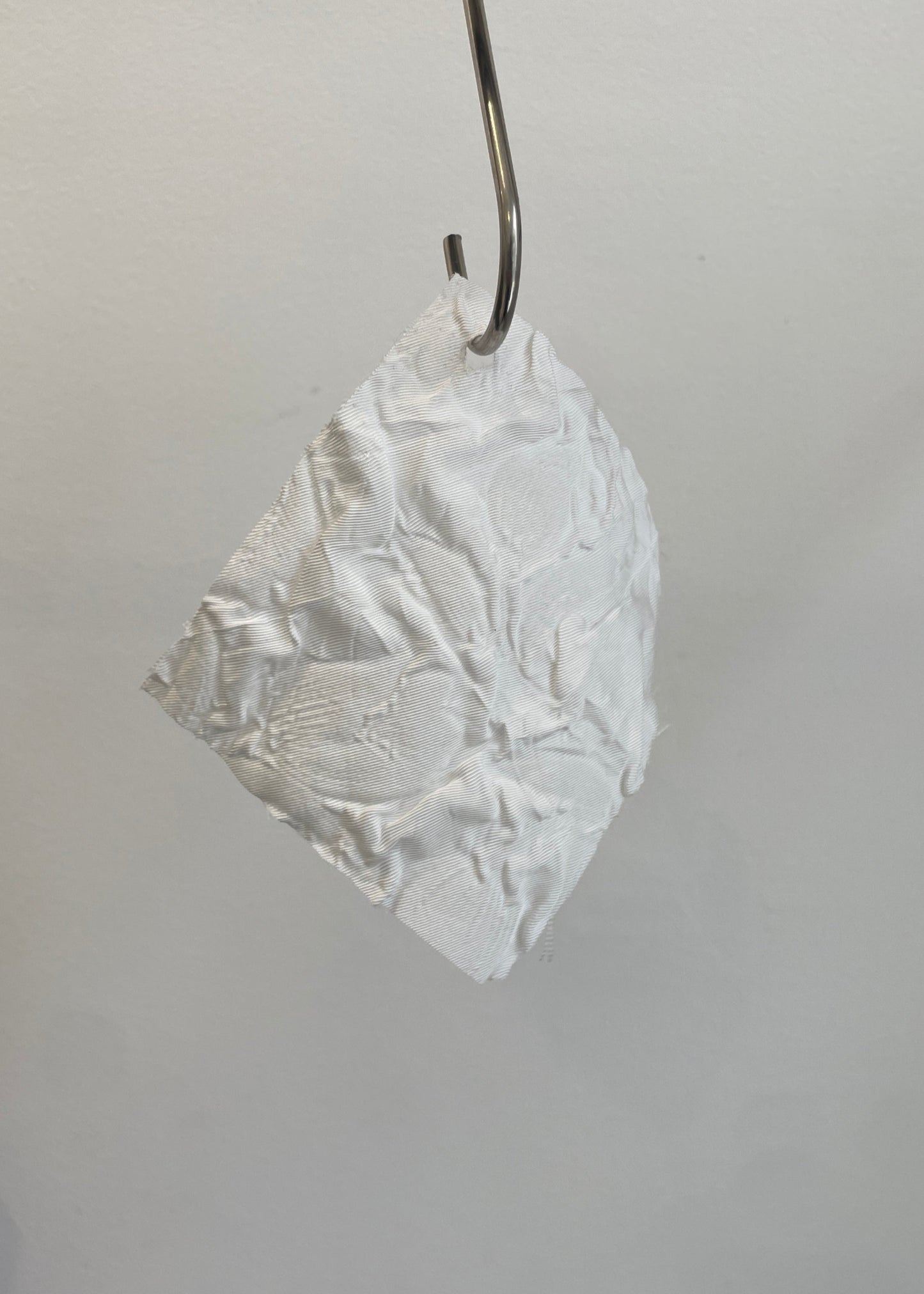 White lace earring hanging from a hook on a gray background