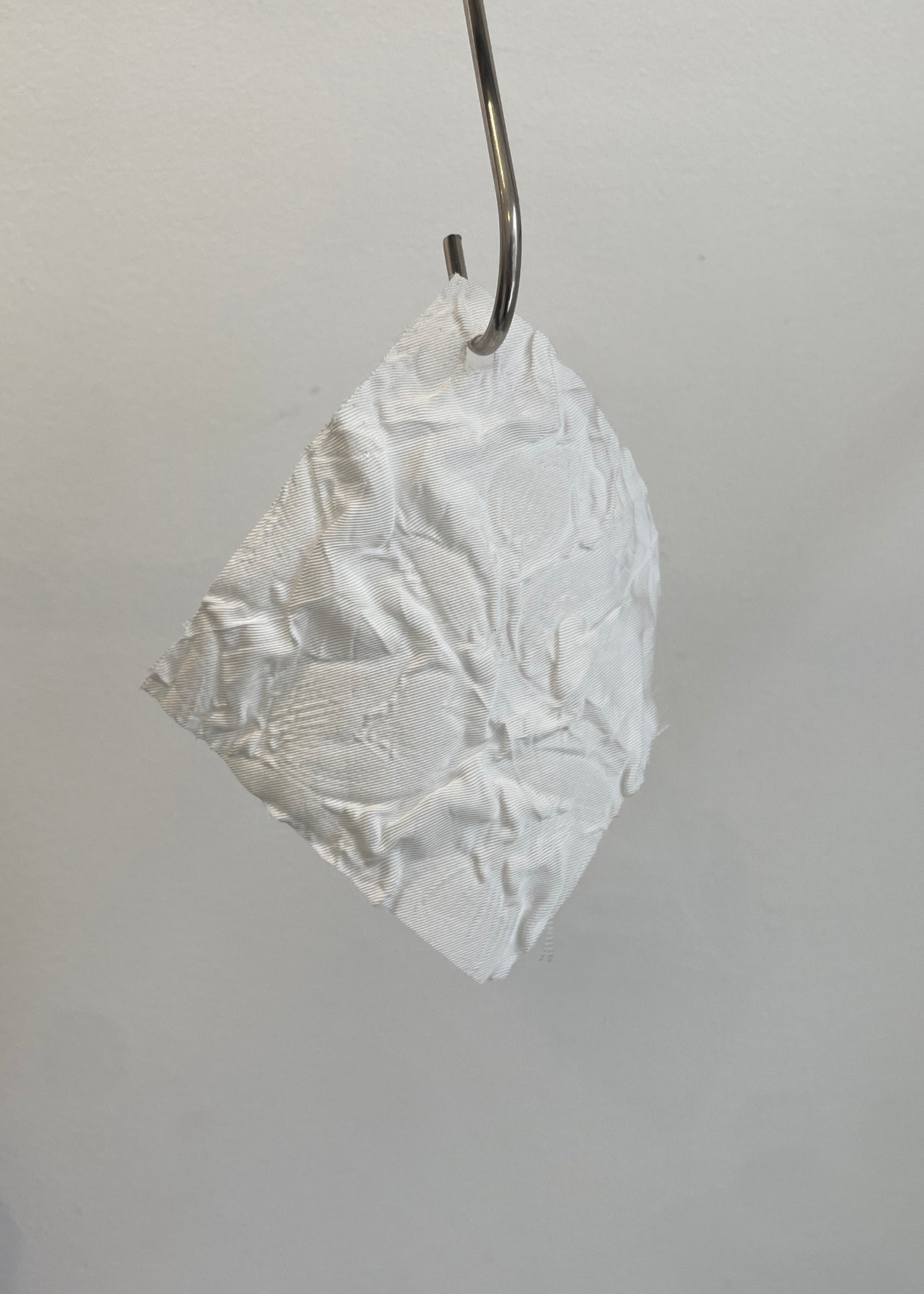 White lace earring hanging from a hook on a gray background