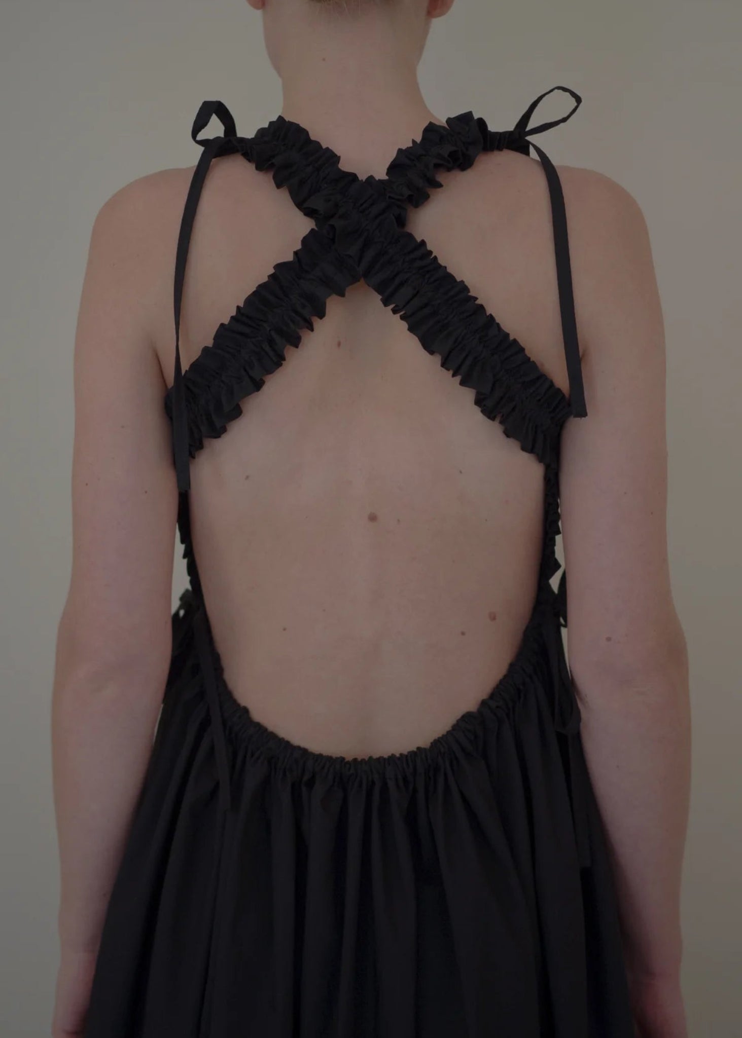 Black dress with criss-cross back design on a plain background