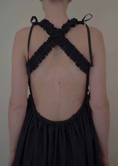 Black dress with criss-cross back design on a plain background