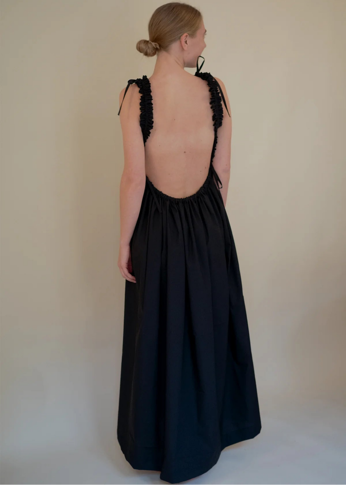 Woman wearing a black dress with floral back design on a plain background