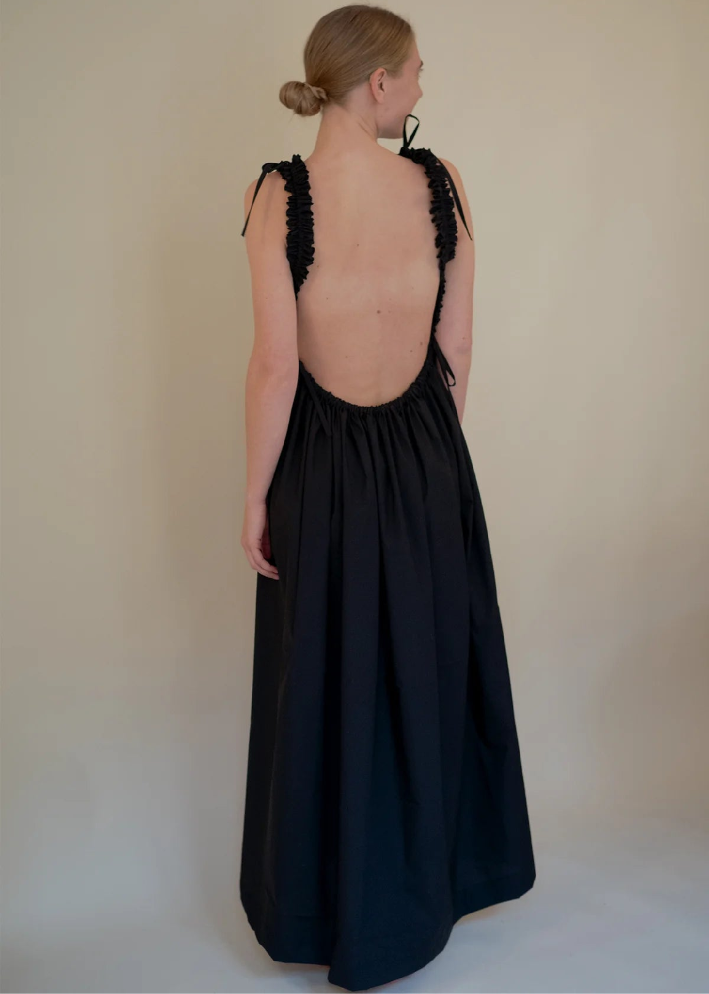 Woman wearing a black dress with floral back design on a plain background