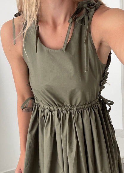 Green dress with thin straps and tie details on a white background
