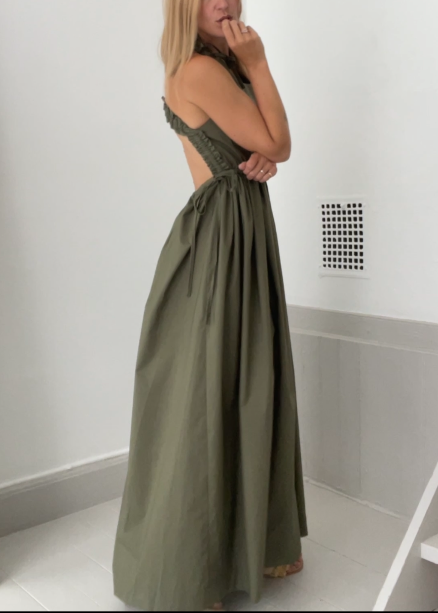 Woman wearing a green dress standing in a bathroom.