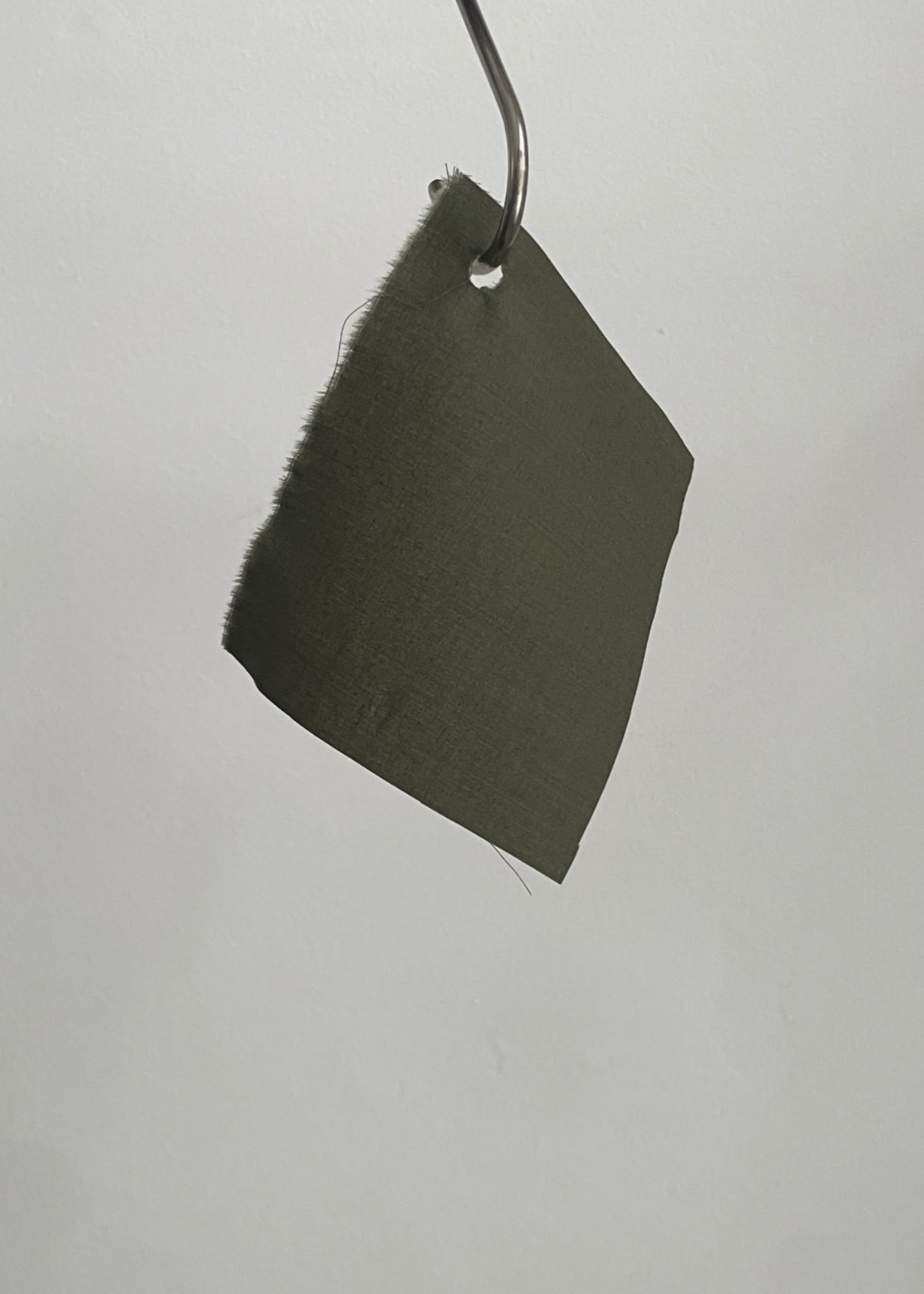 Dark green fabric sample hanging on a rod against a light gray background