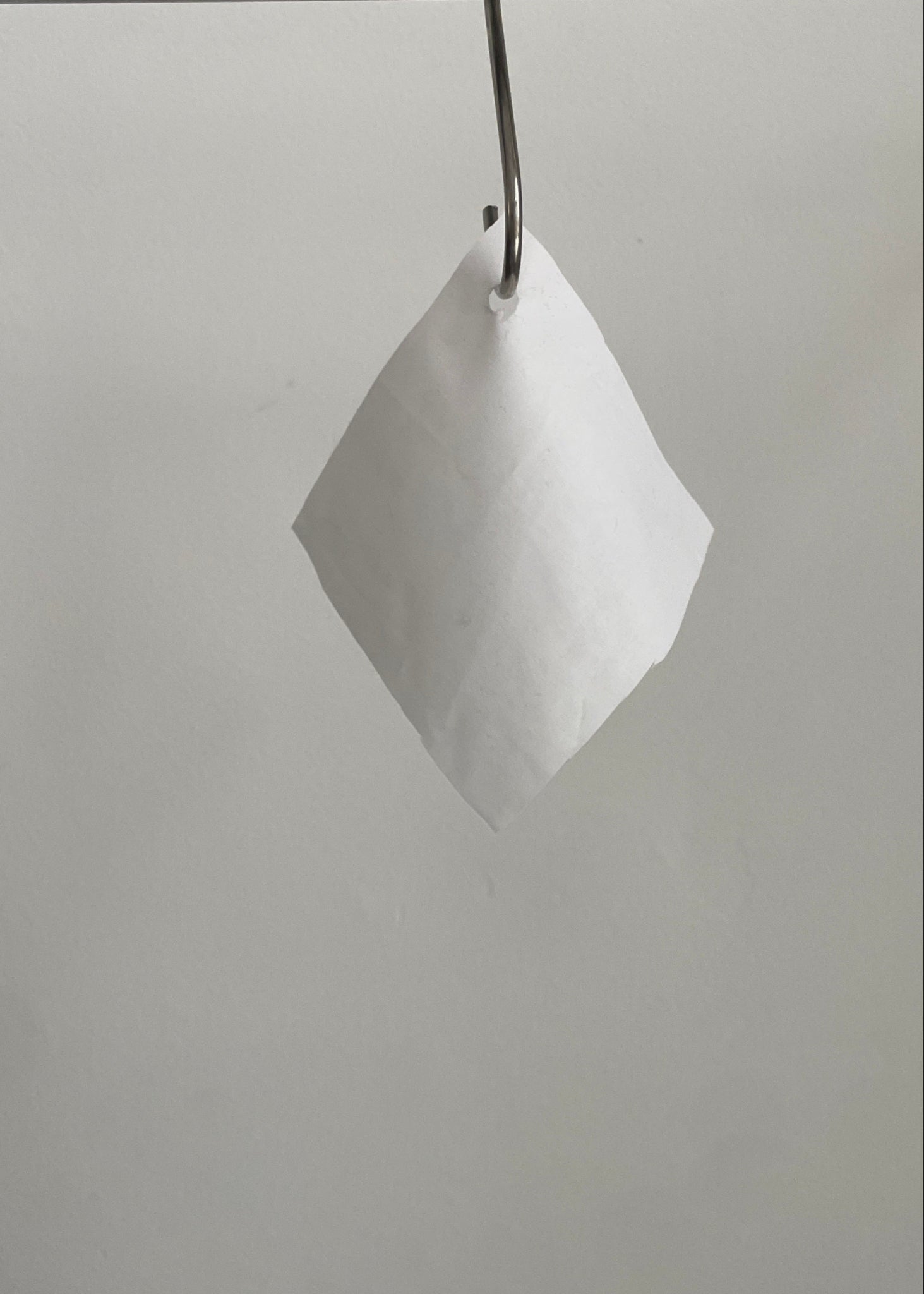 White geometric swatch hanging from a metal rod against a plain background