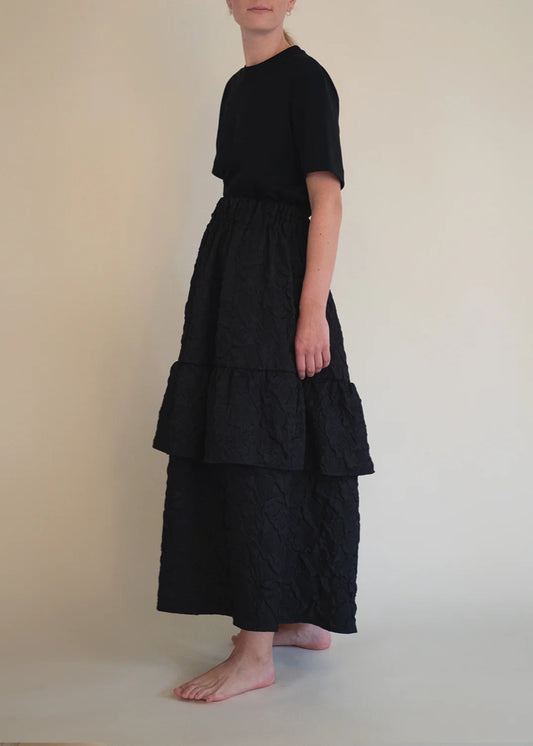 Person wearing a black tiered dress against a plain background