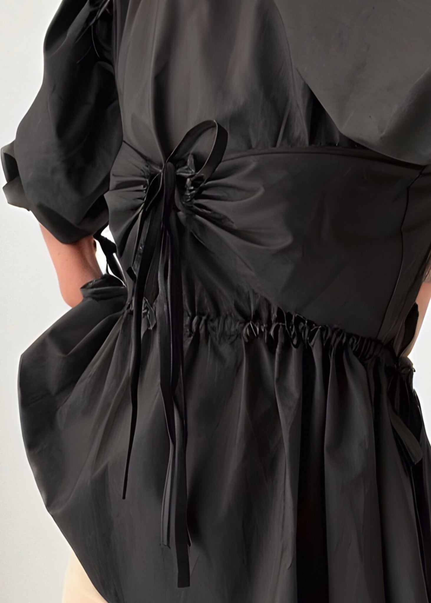 Black top with a bow detail on a mannequin against a white background