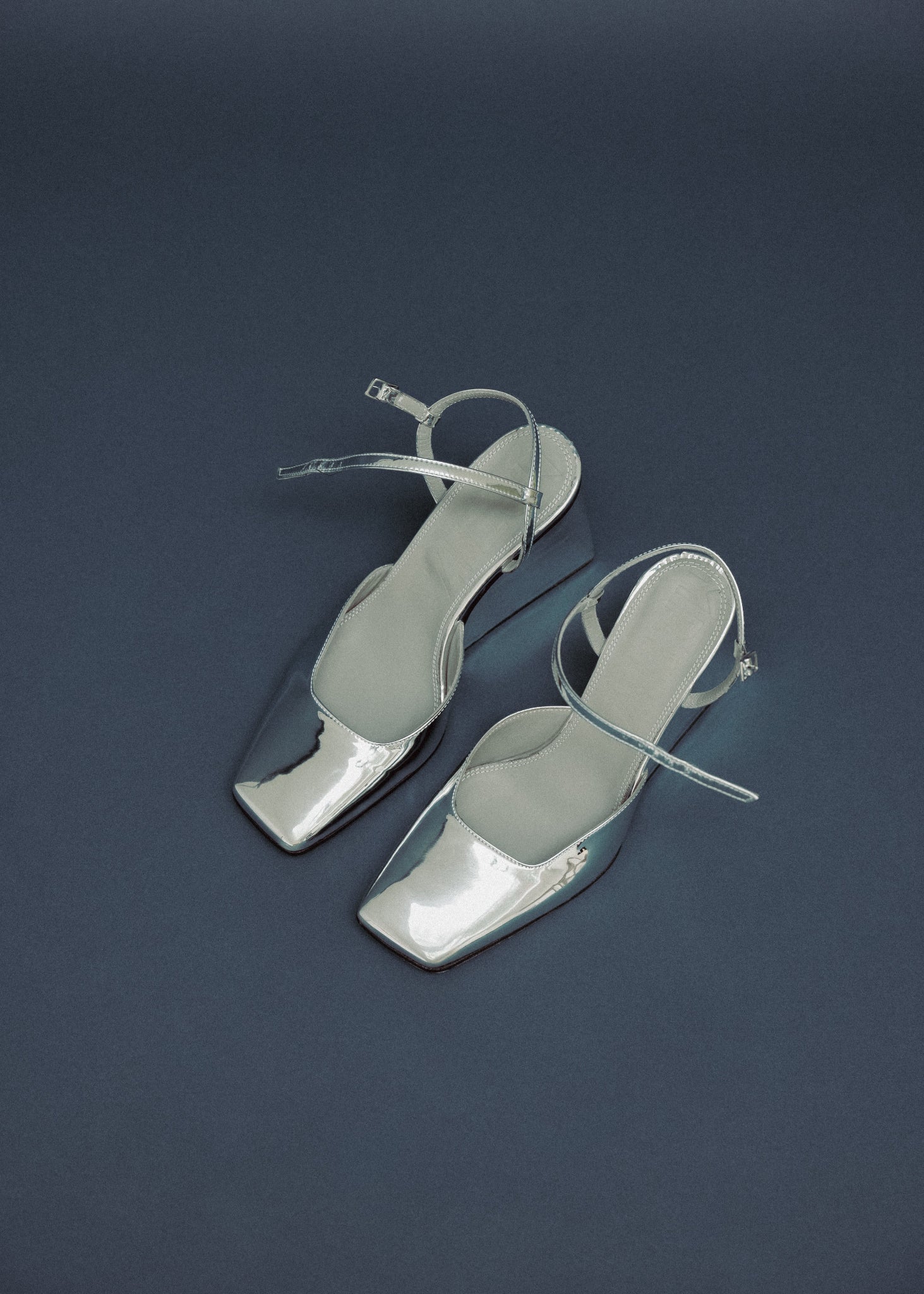 Pair of silver high-heeled sandals on a dark blue background