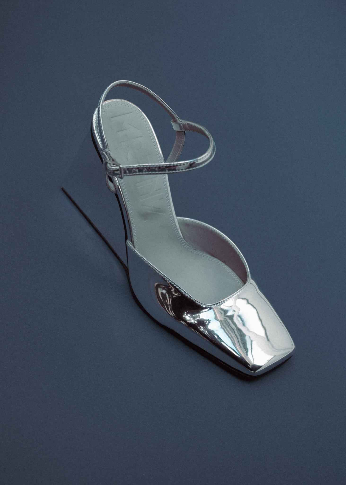 Silver high-heeled shoe on a dark blue background
