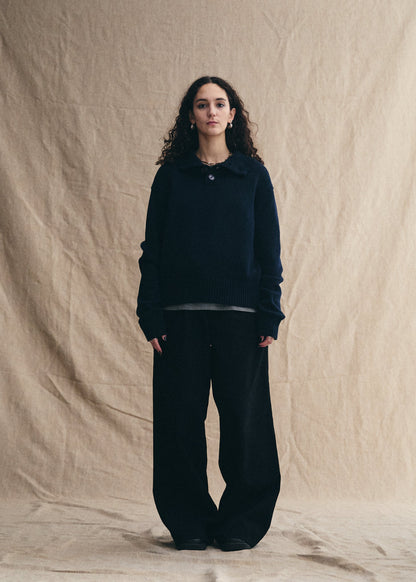 Person wearing a black outfit against a beige background