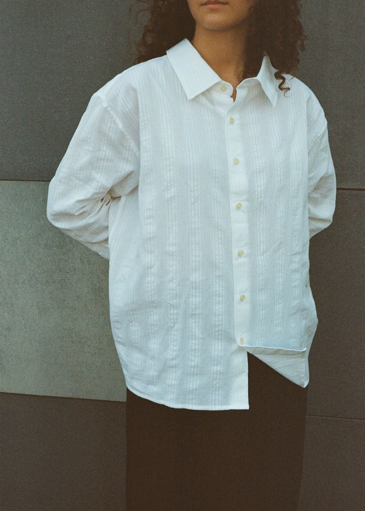 Person wearing a white button-up shirt against a neutral background